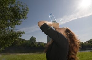 Femme s’hydratant en extérieur pendant une période de fortes chaleurs estivales.
